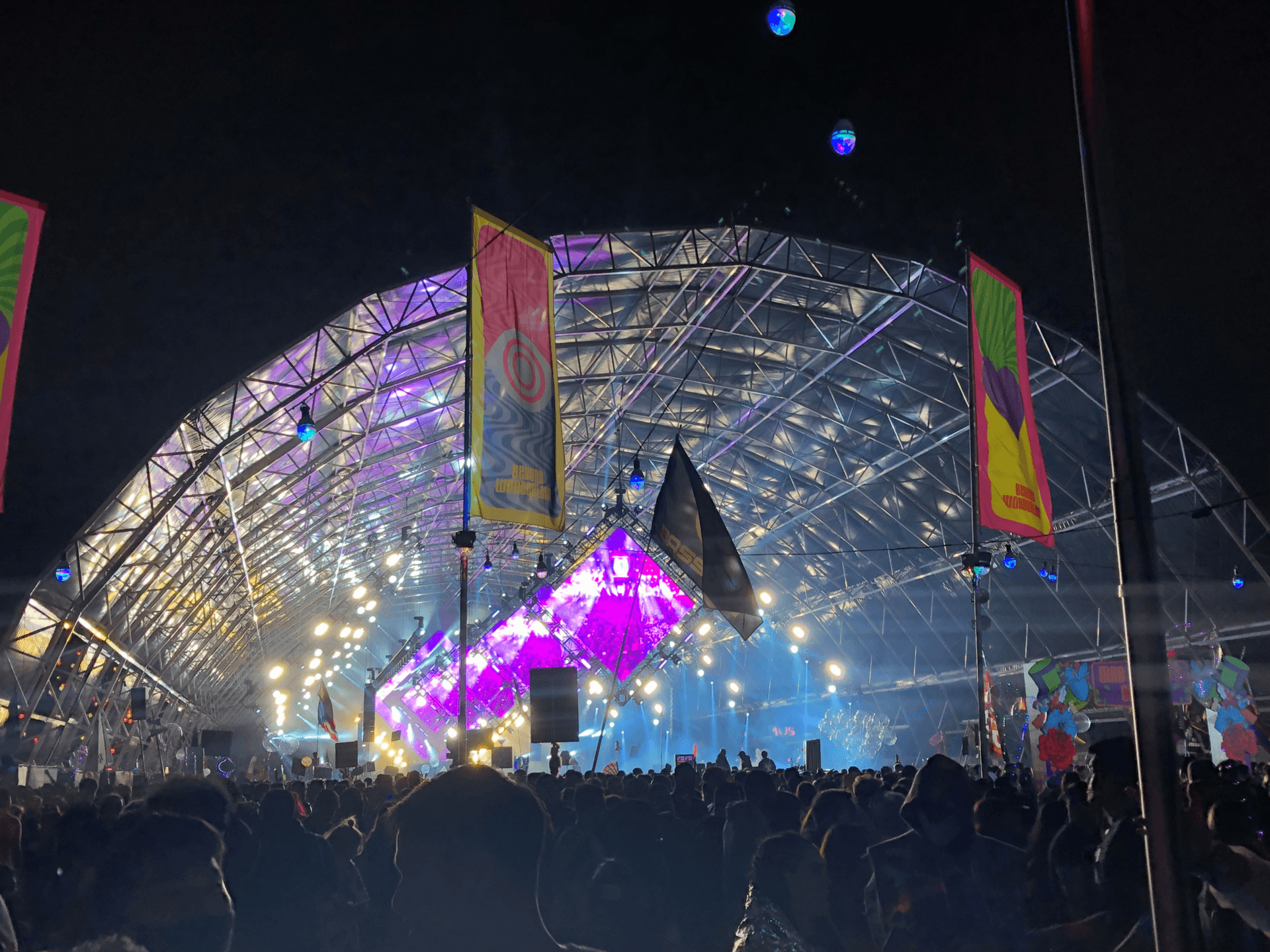 Wide shot of the Mad Hatter's Castle stage at night with fireworks above the crowd at Beyond Wonderland SoCal
