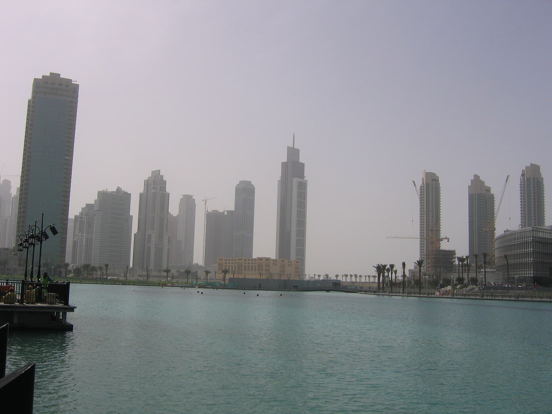 The Dubai Mall and Burj Khalifa with the Dubai Fountain at dusk, wide shot from the Burj Lake promenade