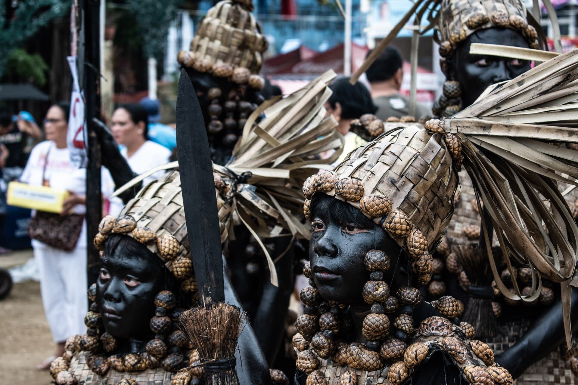 Spectators lining a Kalibo street behind barriers while a tribe passes in costume