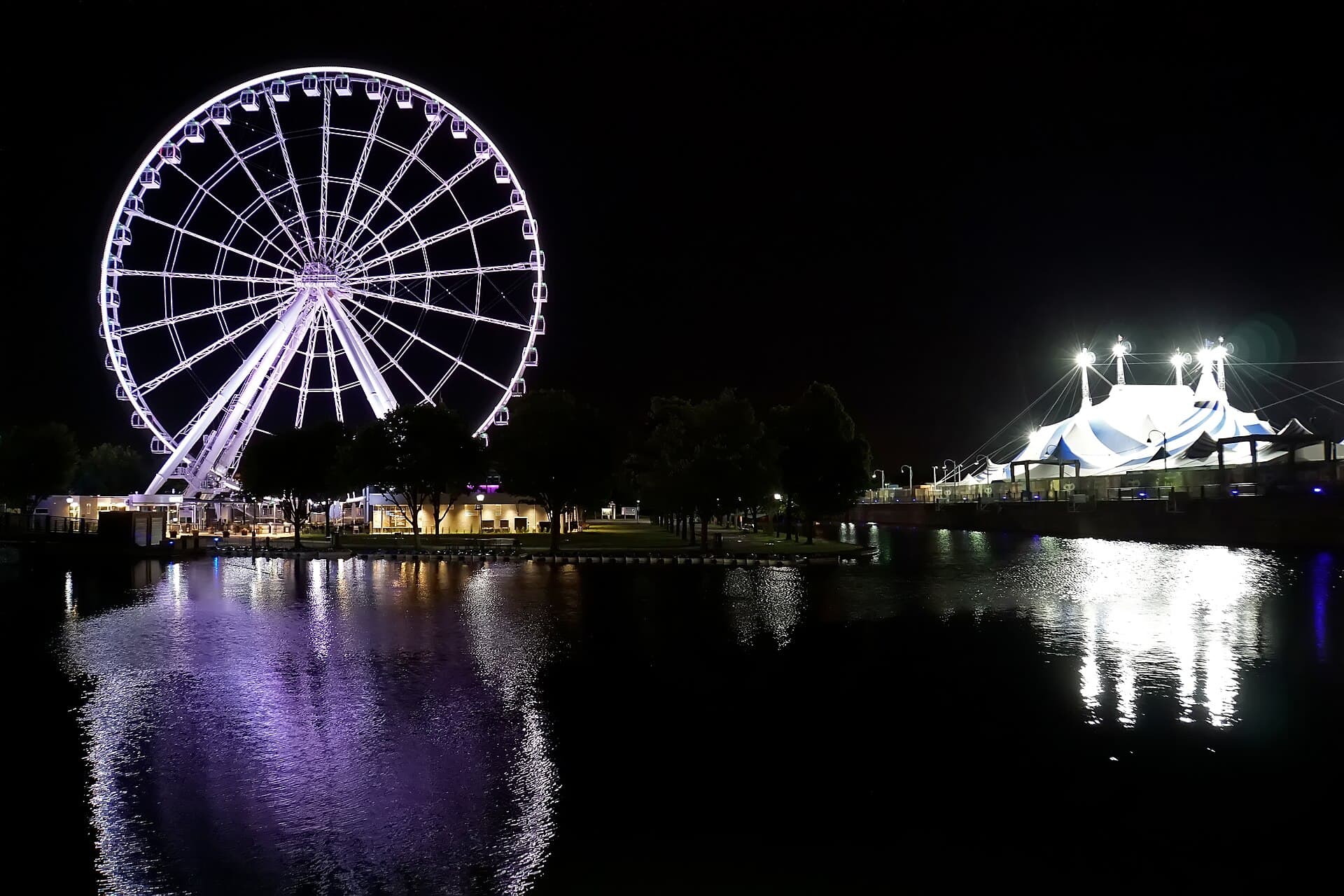 Wide shot of the Jacques-Cartier Pier in Montreal's Old Port lit up at night with the Sapporo Stage and a crowd in winter coats