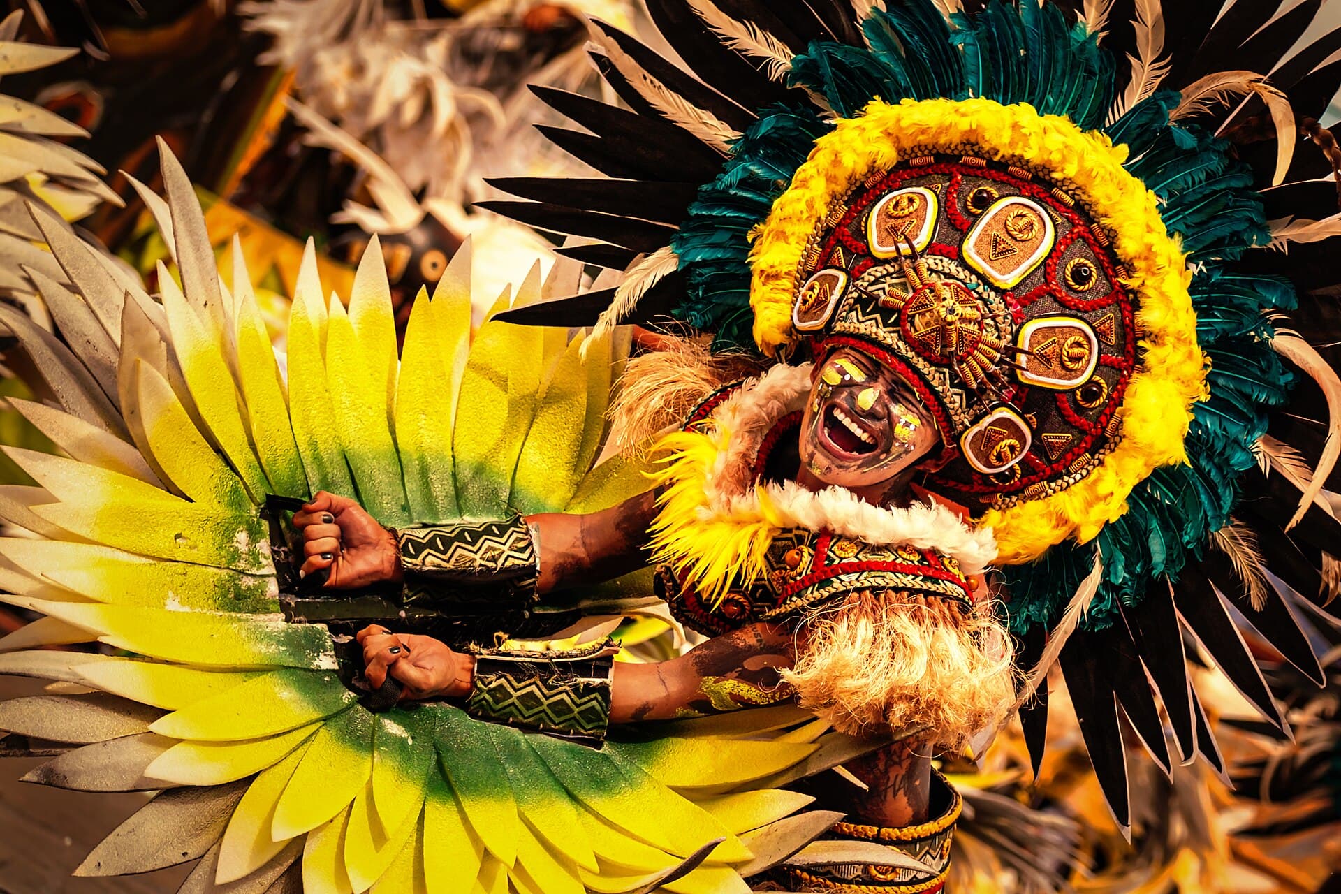 Close portrait of a Dinagyang tribe performer with black face paint and a beaded, feathered headdress