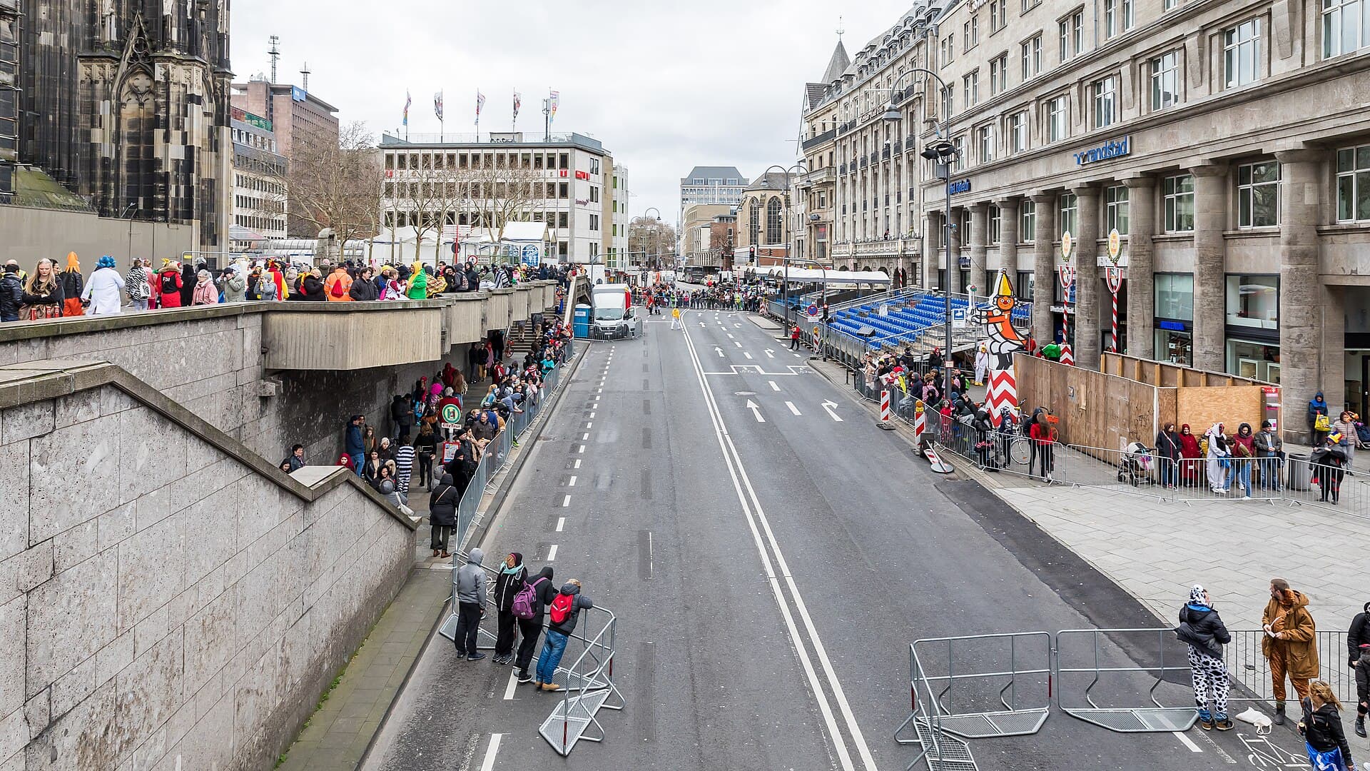 Spectators in winter coats waiting along the Rosenmontagszug route near the Severinstorburg in Cologne