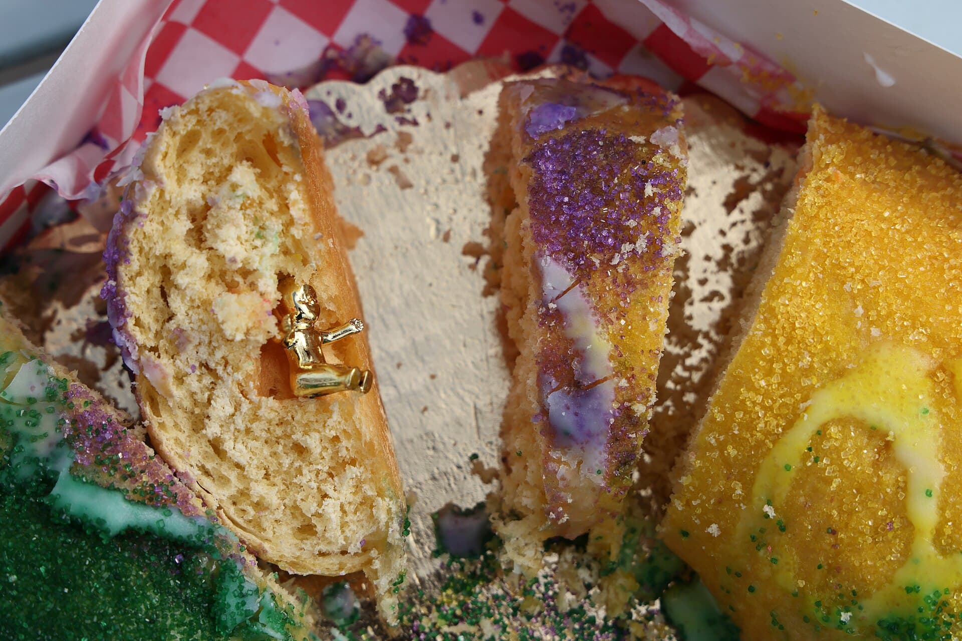 Purple, green and gold iced king cake in an open bakery box in New Orleans