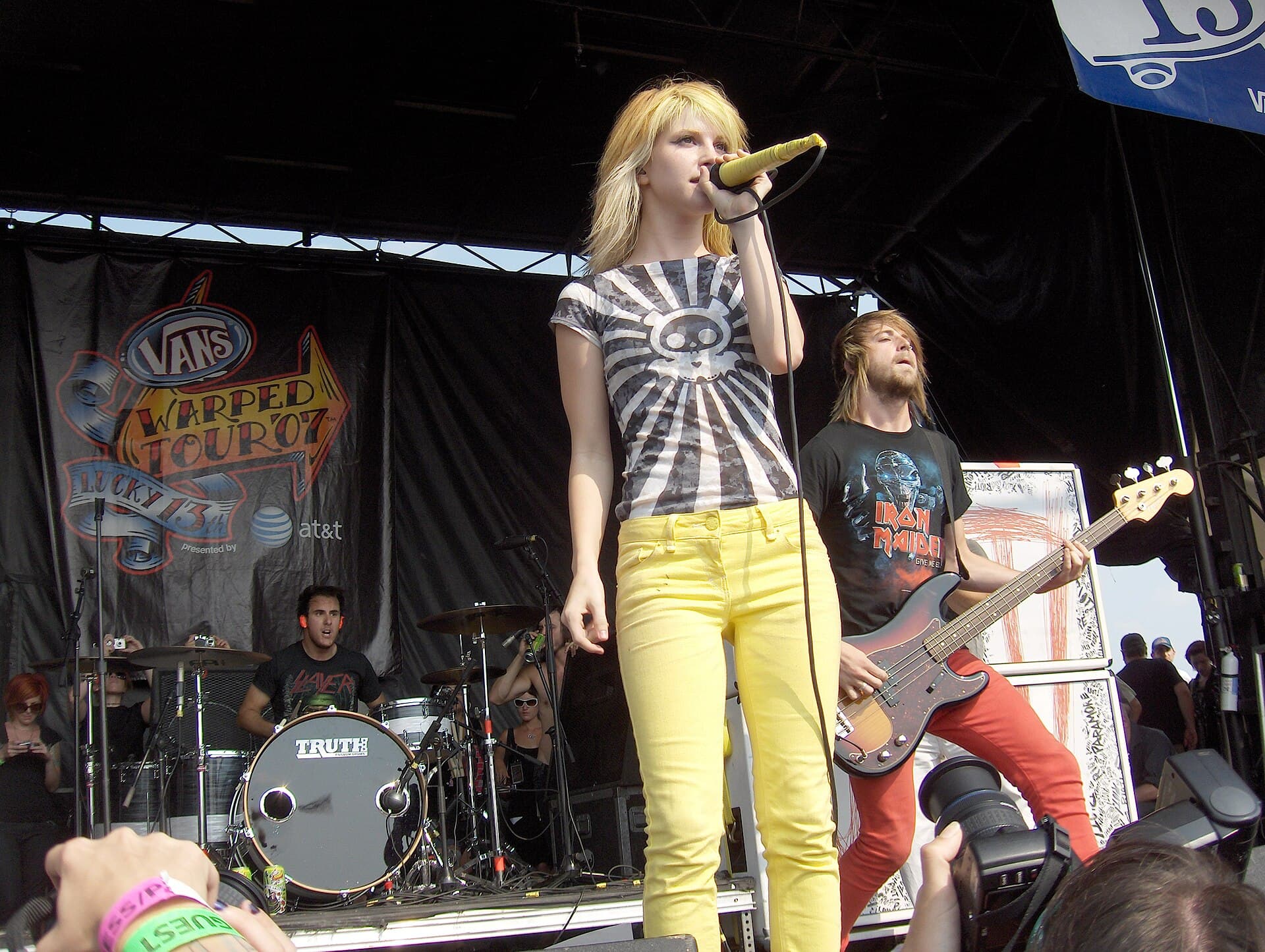Hayley Williams performing on an outdoor festival stage in front of a large crowd at dusk