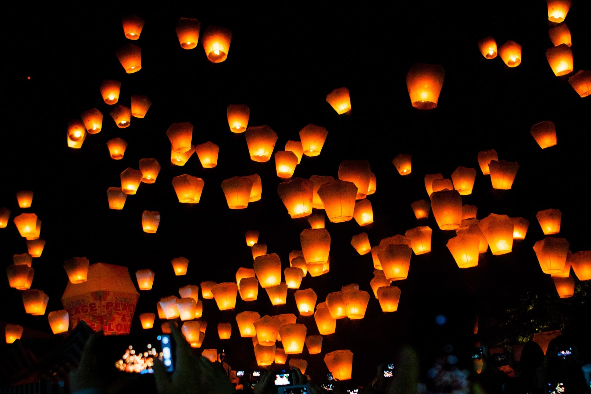 Visitors holding a large paper lantern with handwritten wishes before release at Shifen Sky Lantern Square