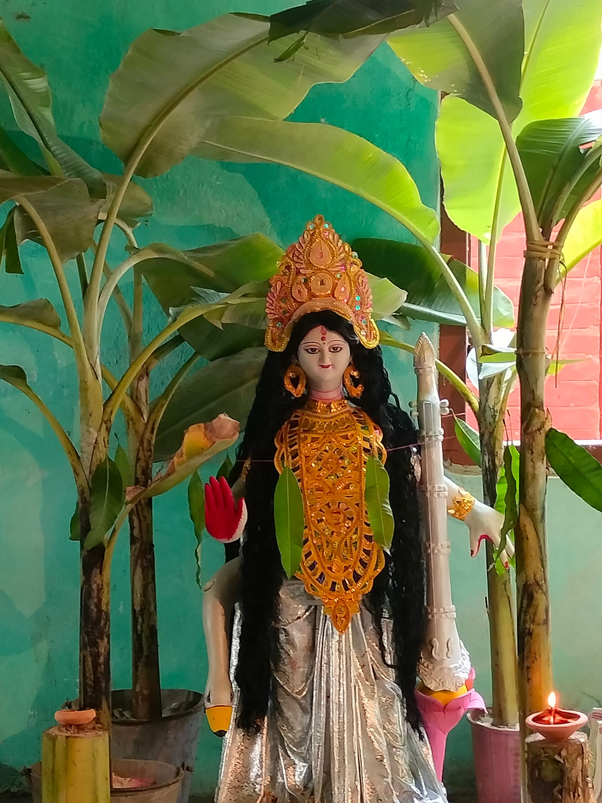 Women in yellow saris offering flowers at a Saraswati Puja anjali in Kolkata