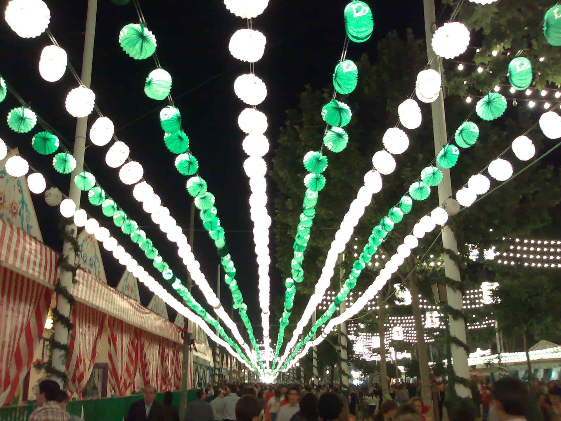 Rows of farolillos paper lanterns over a street of casetas at dusk