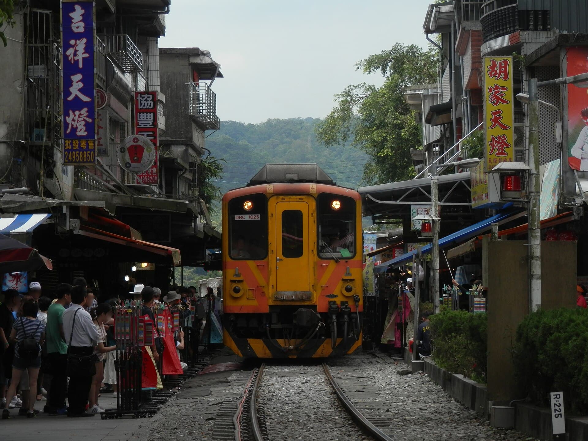 Shifen Station and a Pingxi Line train passing between the shop fronts of Shifen Old Street