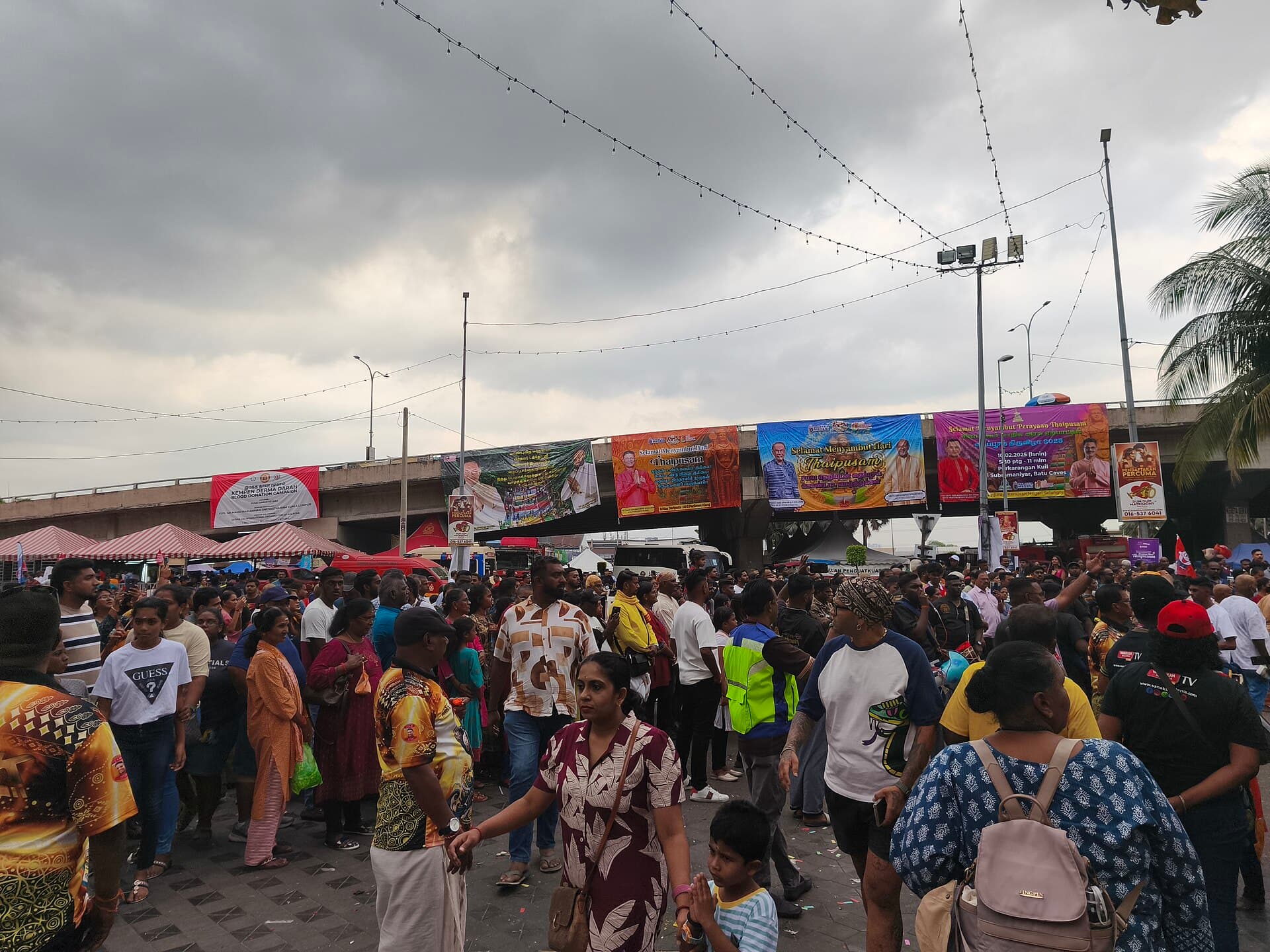A kavadi bearer with a peacock-feather frame climbing the steps surrounded by supporters