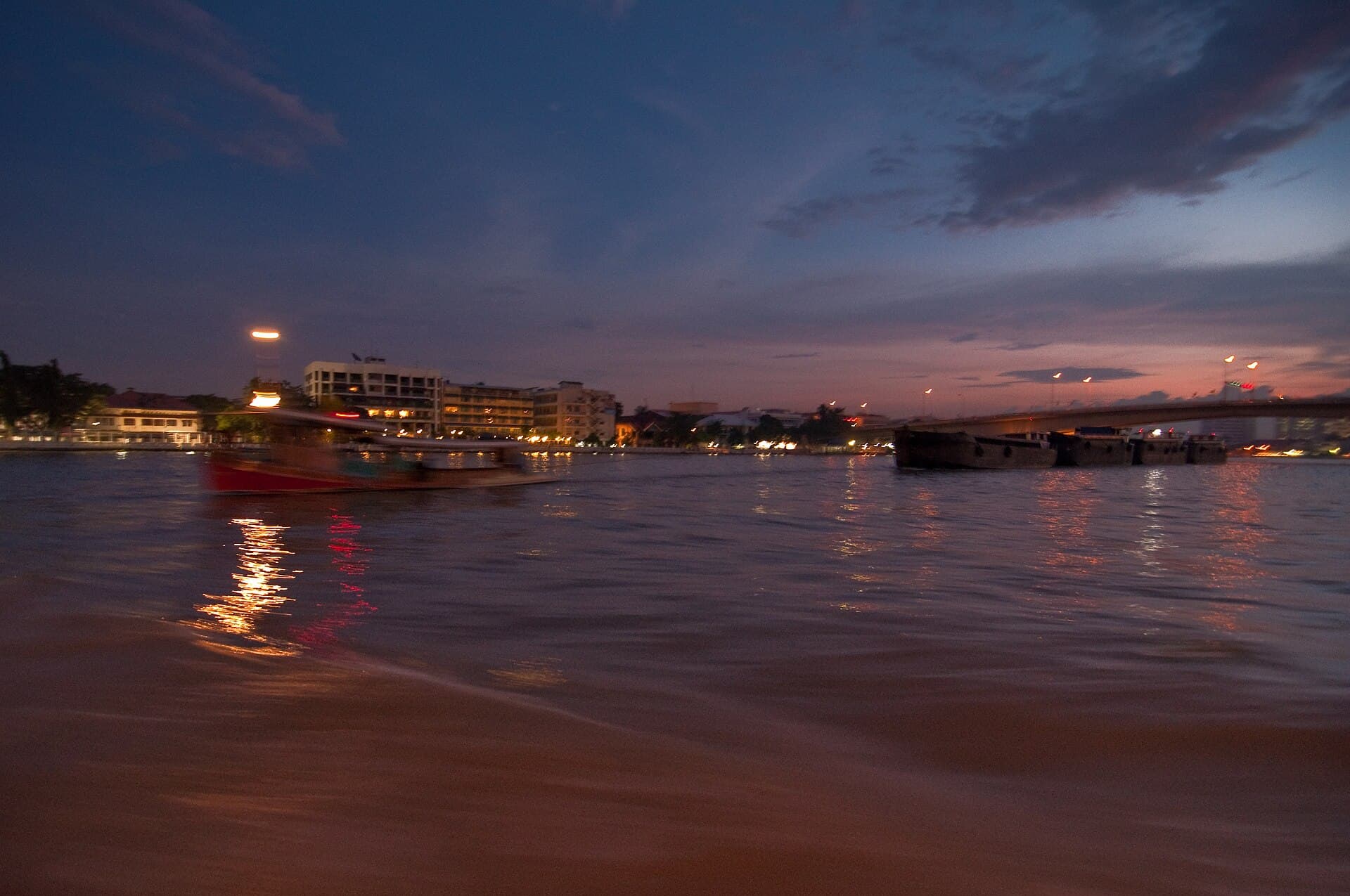 Chao Phraya Express Boat pulling into Tha Chang pier with the Grand Palace roofs behind