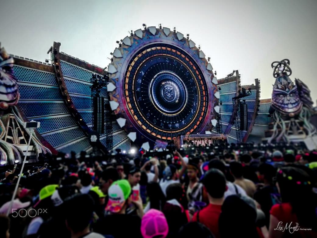 A crowd at night holding phones above their heads in front of a lit main stage