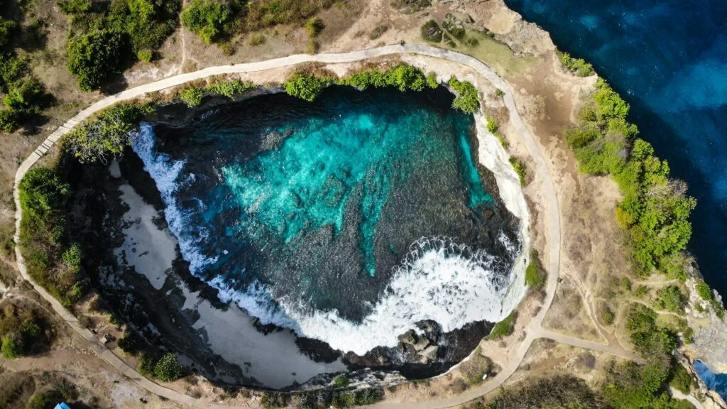 Aerial view of Broken Beach in Nusa Penida, Bali, showcasing the natural rock arch, turquoise waters, and dramatic coastal landscape