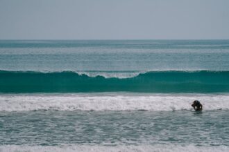 Surfer walking along the sea shore at Kuta Beach during golden hour in Bali, Indonesia